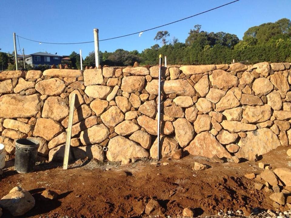 A Large Stone Wall Is Being Built In A Field — Australian Rock Walls In Hervey Bay, QLD