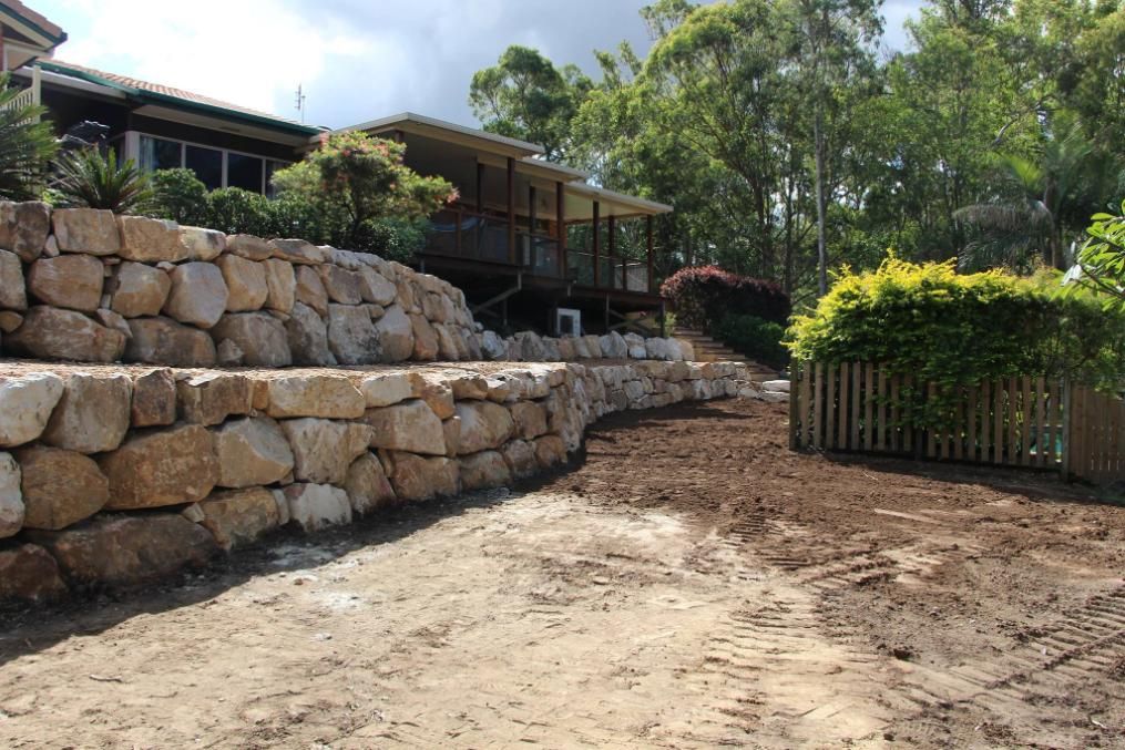 A Large Stone Wall Is Being Built In Front Of A House — Australian Rock Walls In Upper Coomera, QLD