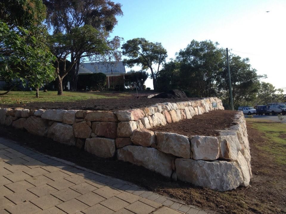 A Stone Wall With A Brick Walkway In Front Of It — Australian Rock Walls In Burleigh Heads, QLD