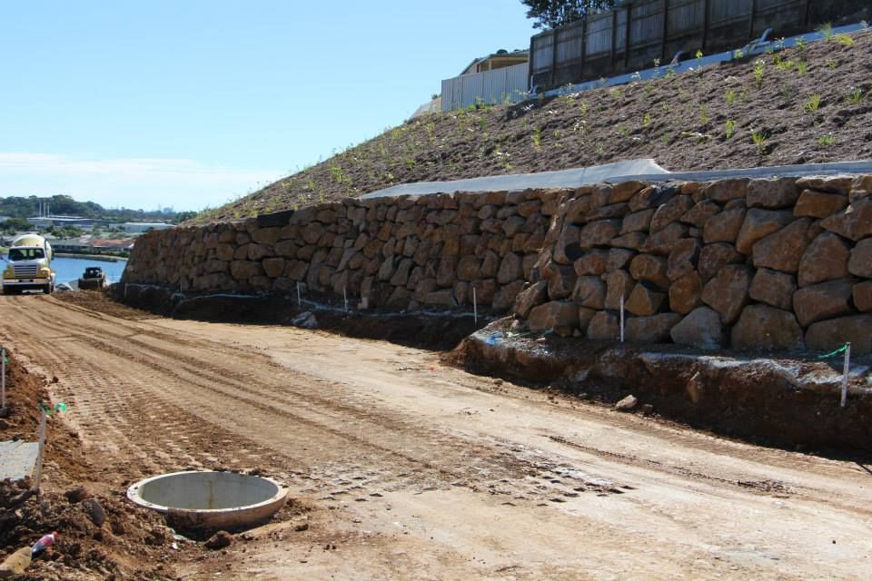 A Dirt Road With A Large Rock Wall On The Side Of It — Australian Rock Walls In Sunshine Coast, QLD