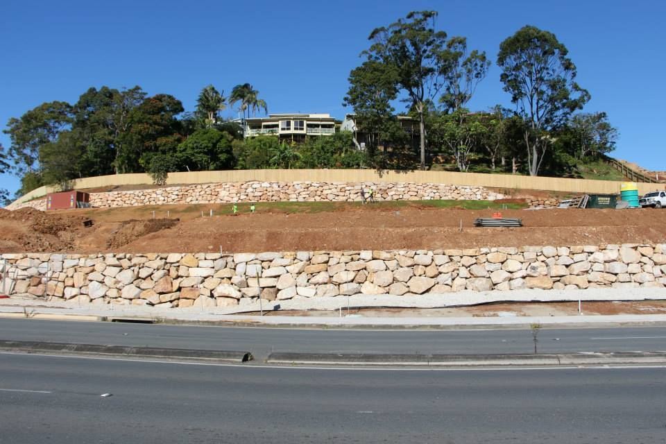 A Large House Sits On Top Of A Hill Behind A Stone Wall — Australian Rock Walls In Cleveland, QLD