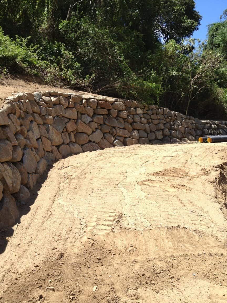 A Dirt Road With A Stone Wall On The Side Of It — Australian Rock Walls In Burleigh Heads, QLD