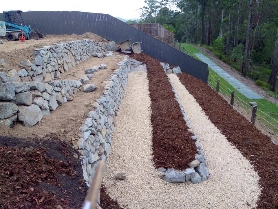 A Fence Is Being Built On A Hill With Rocks And Gravel — Australian Rock Walls In Bilambil, NSW