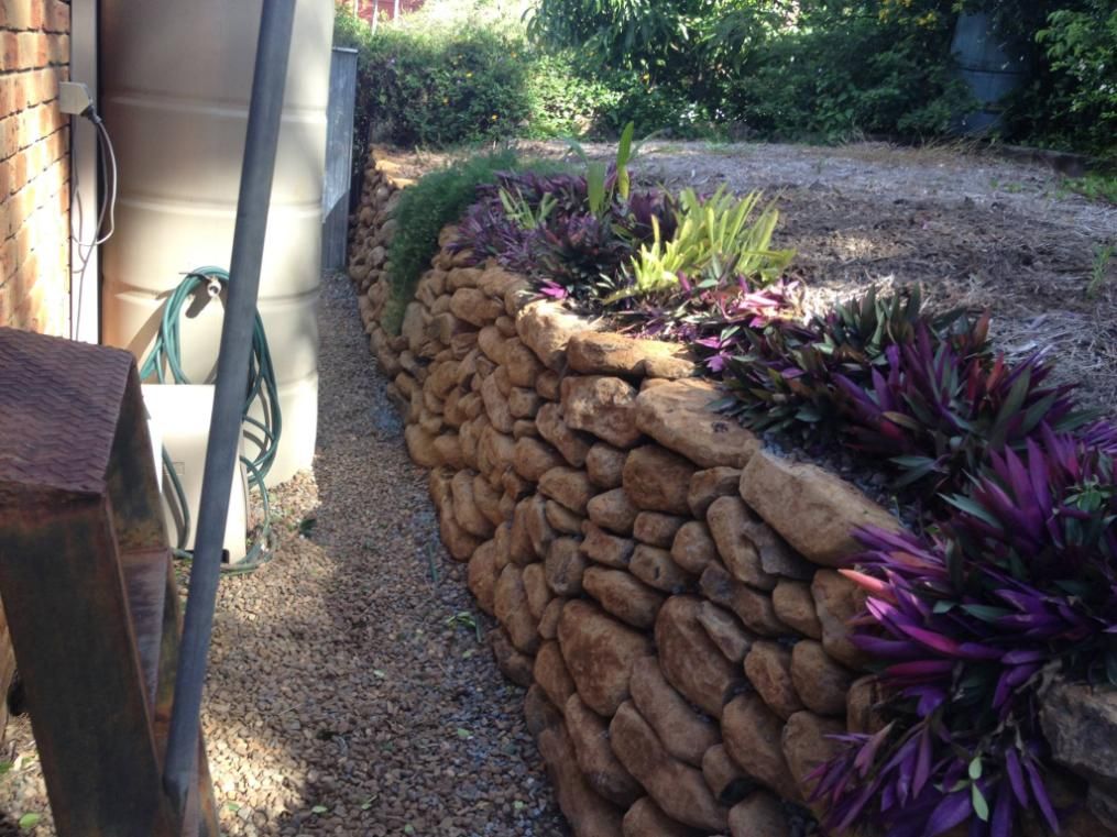 A Stone Wall Surrounds A Garden With Purple Flowers — Australian Rock Walls In Bonogin, QLD