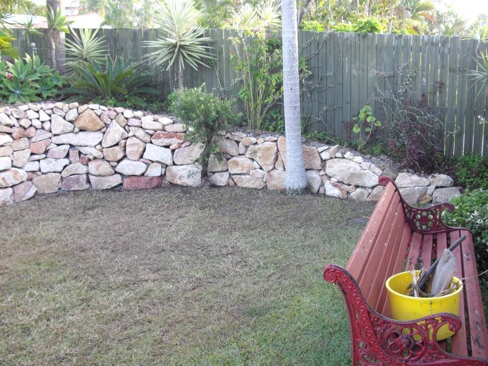 A Bench With A Yellow Bucket On It In A Garden — Australian Rock Walls In Burleigh Heads, QLD