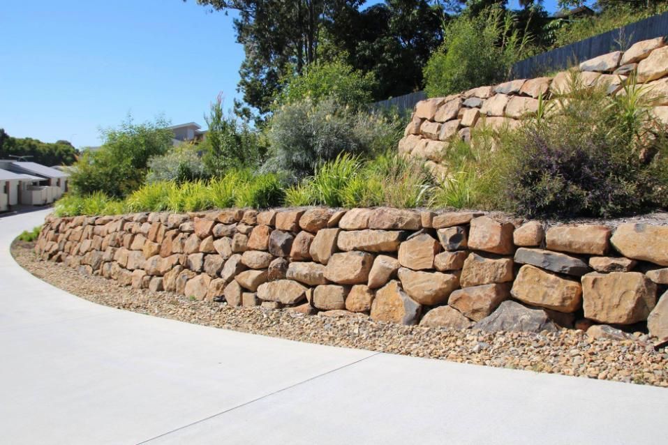 A Rock Wall on the Gold Coast Is Surrounded By Trees And Bushes On The Side Of A Road — Australian Rock Walls In Gold Coast, QLD
