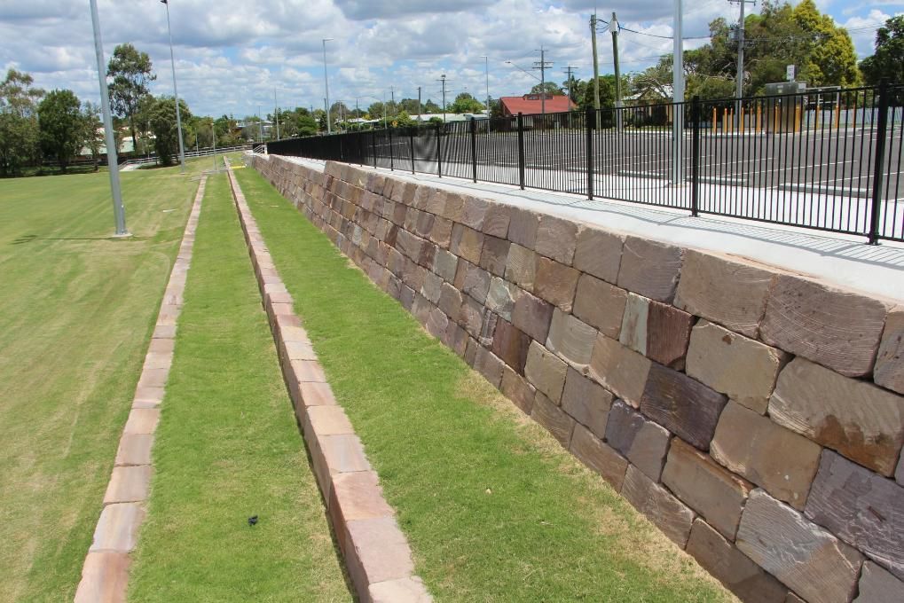 A Block Retaining Wall on the Gold Coast Surrounds A Lush Green Field — Australian Rock Walls In Gold Coast, QLD