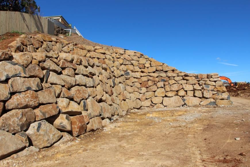 A Large Pile Of Rocks Is Sitting On Top Of A Dirt Hill — Australian Rock Walls In Tallai, QLD