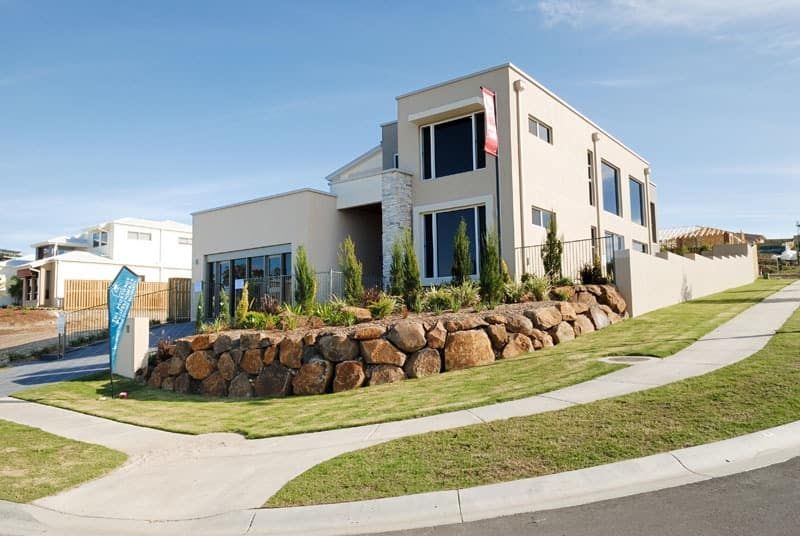 Boulder retaining wall and landscaped garden bed at the front of a modern two-storey home, a popular retaining wall Gold Coast design for sloped front yards.