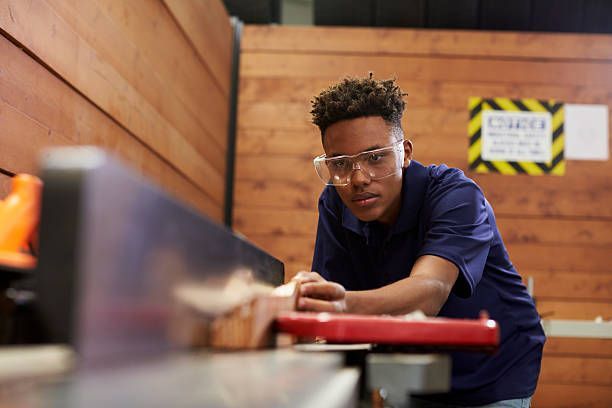 Carpenter operating a wood planer machine in workshop