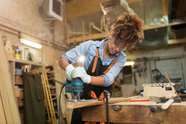 Female carpenter using a jigsaw tool on wood