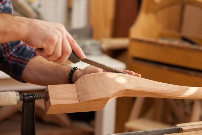 Woodworker shaping a furniture leg with a file