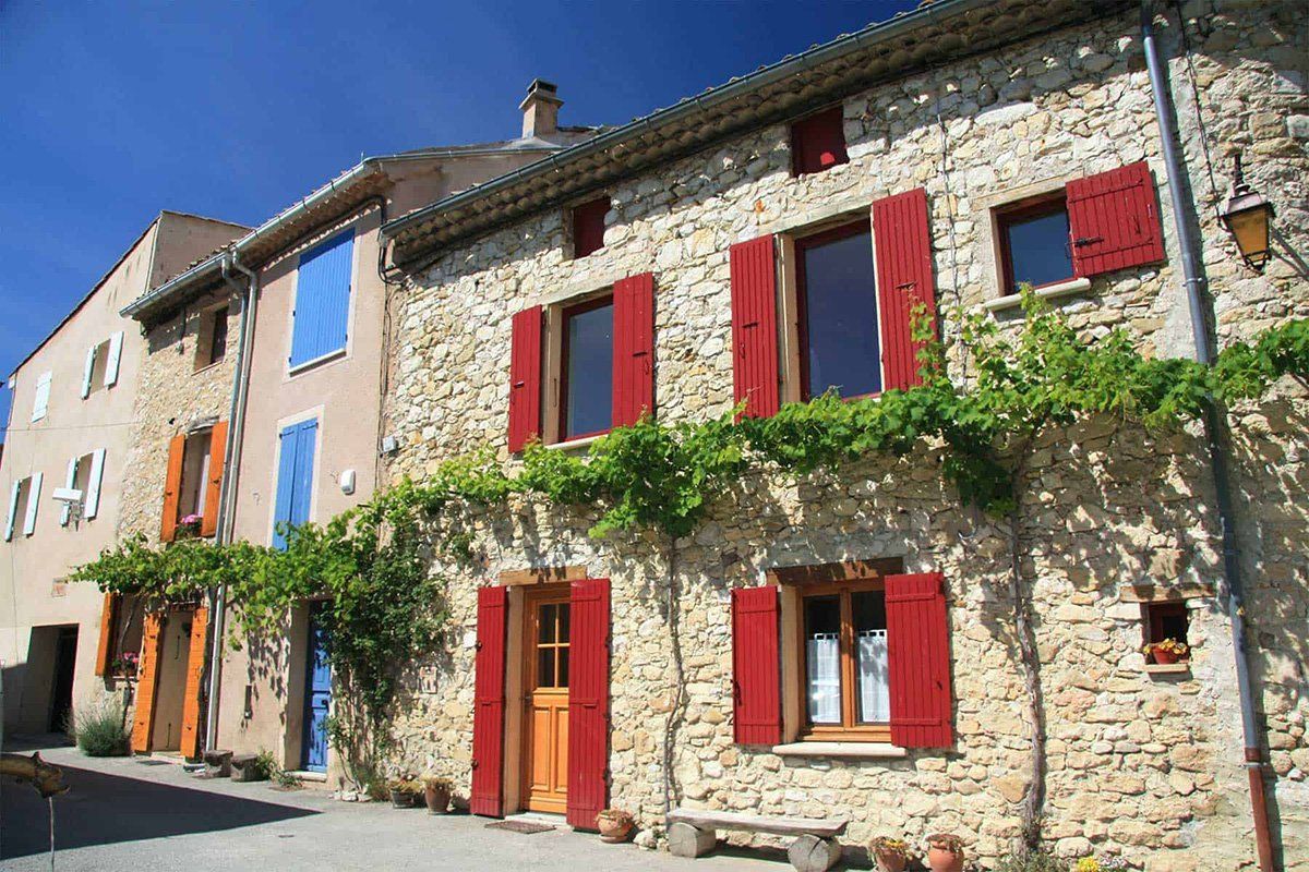 Un edificio in pietra con persiane rosse alle finestre