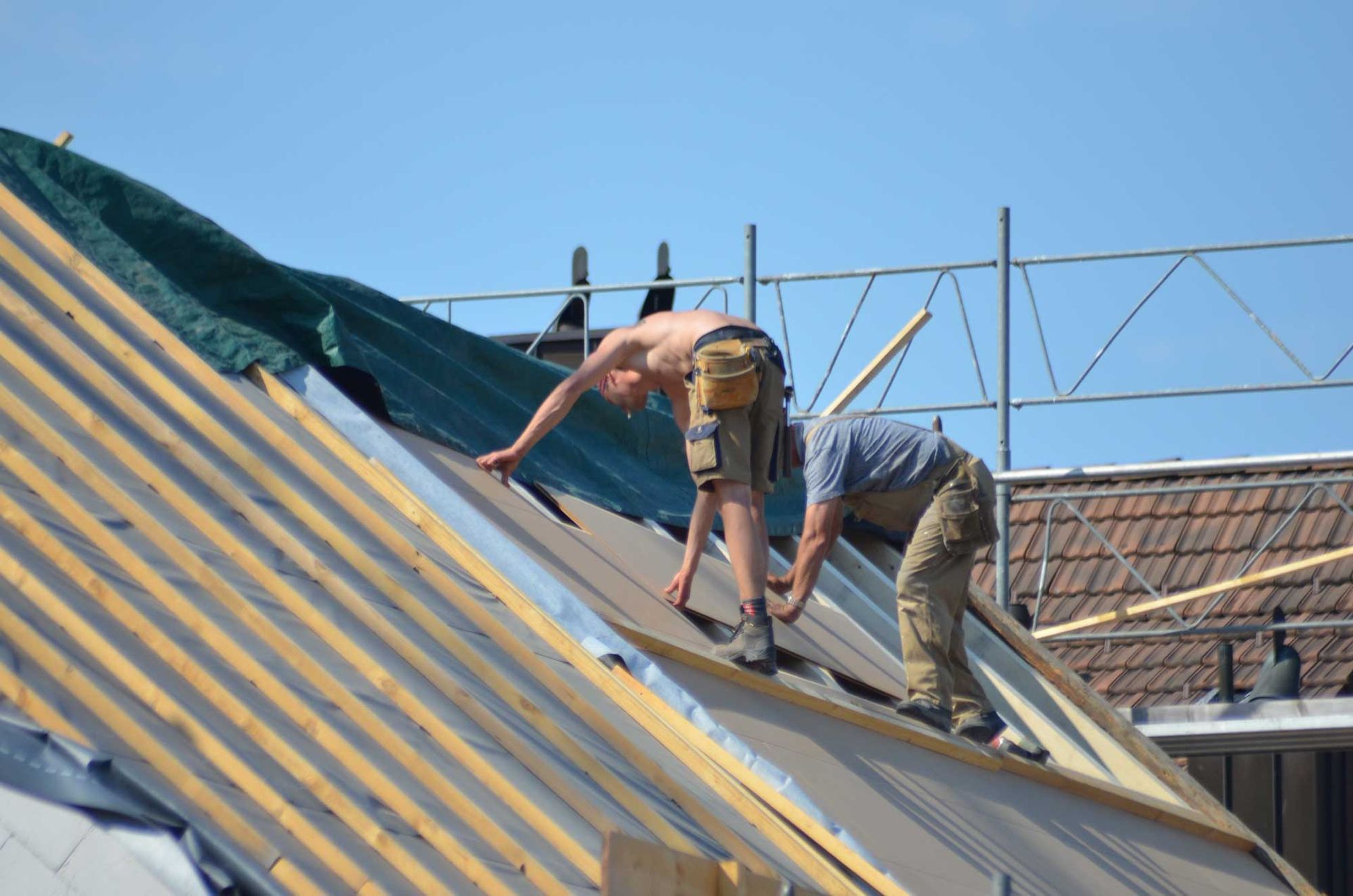 Two men using tools for maintenance work by a roofing repair contractor on a residential home roof.