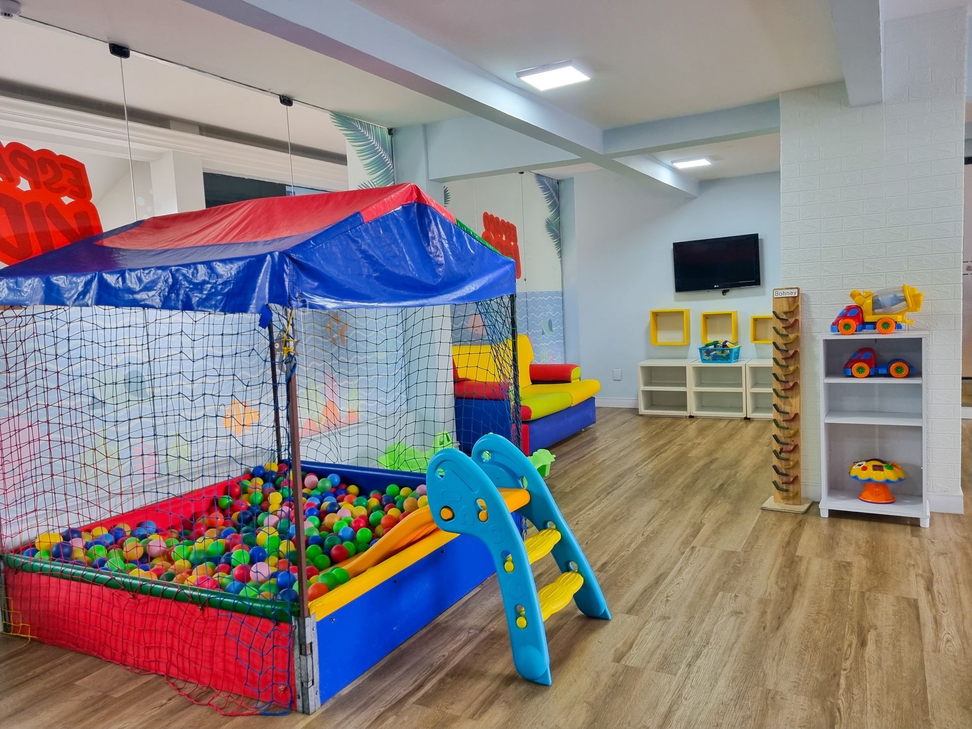Área de recreação infantil interna com piscina de bolinhas, escada para escalar e brinquedos coloridos.