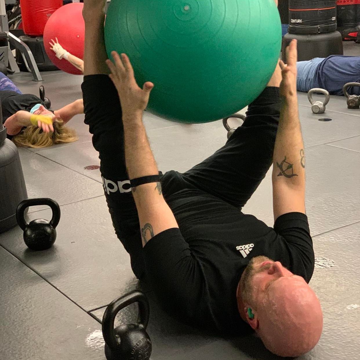A man is laying on the floor holding a green exercise ball.