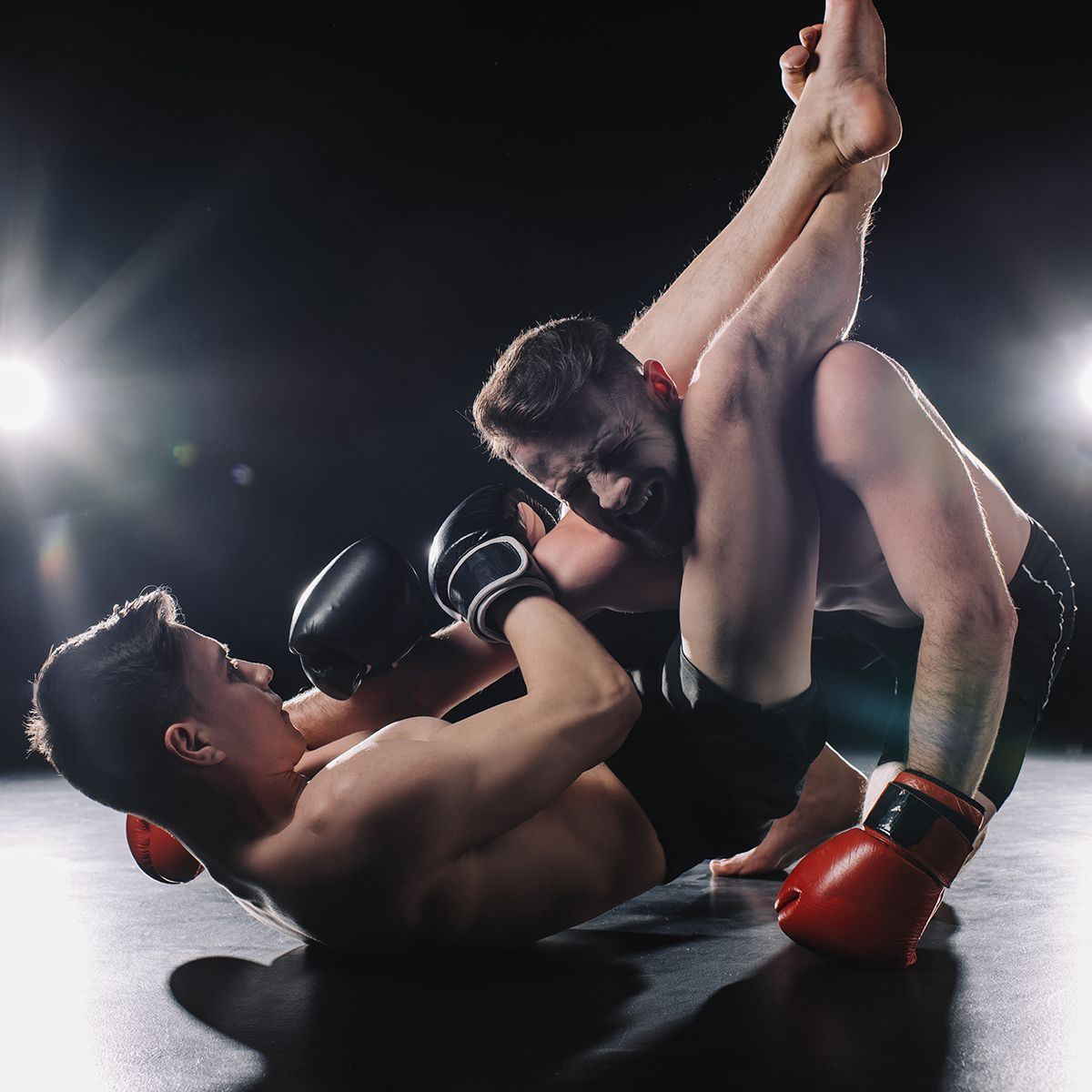 Two men are wrestling in a ring with boxing gloves on.