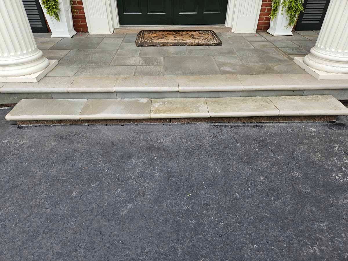 Front porch with stone steps, white columns, and a blacktop driveway in front.