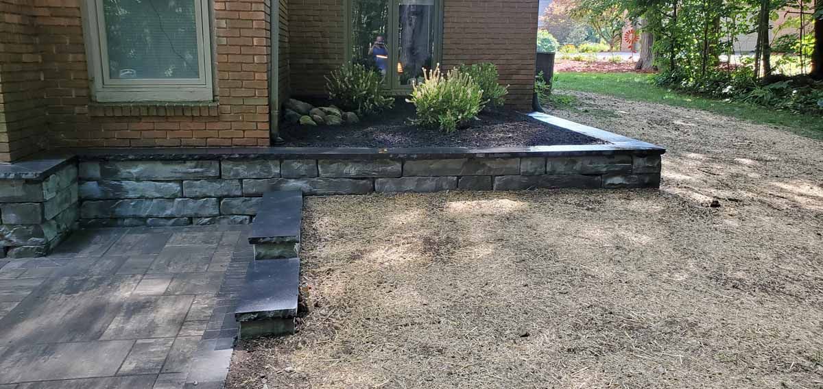Brick house patio with stone steps and a gravel yard in front