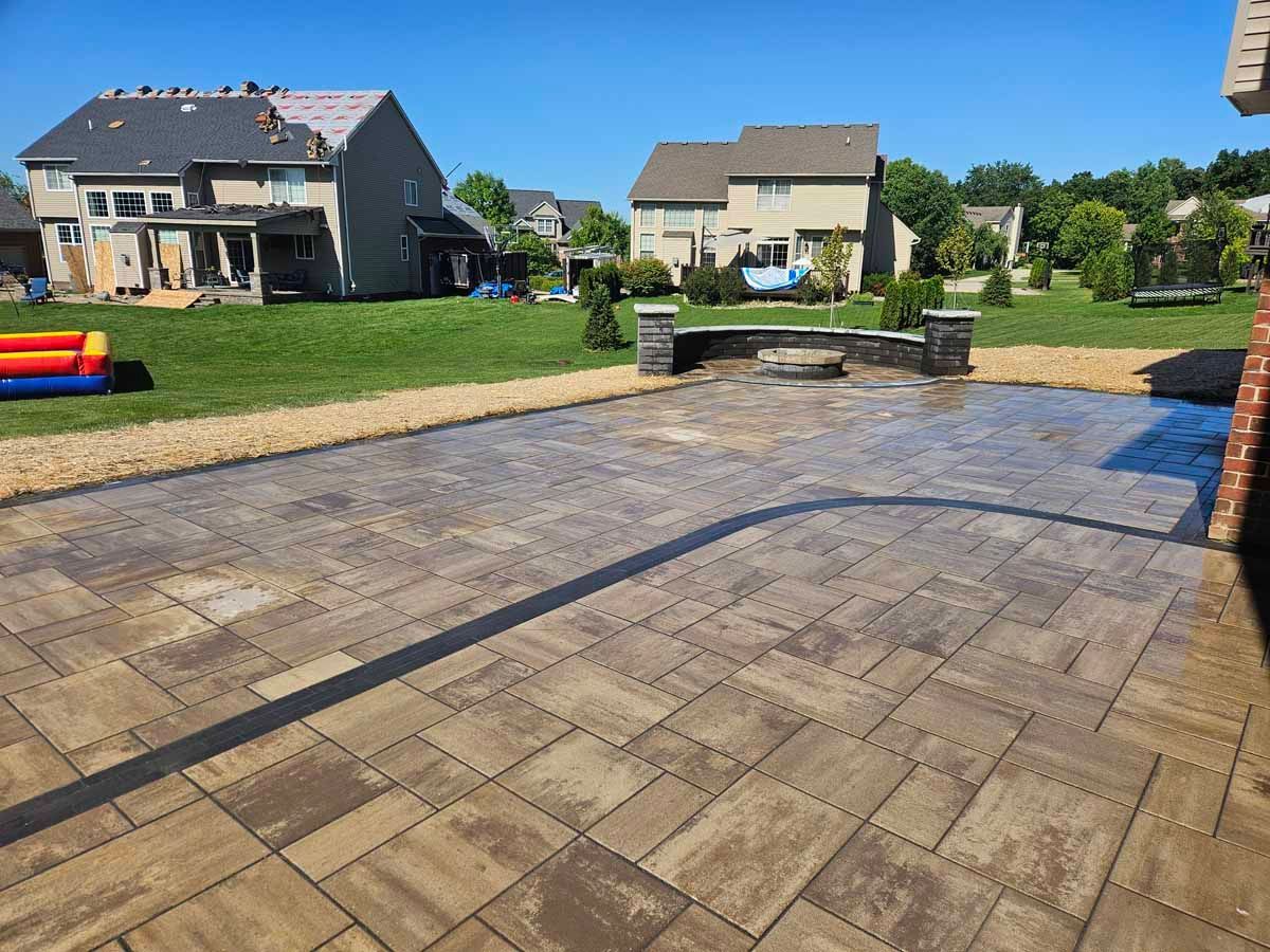 Backyard patio with stone pavers, raised garden beds, and suburban houses in the background