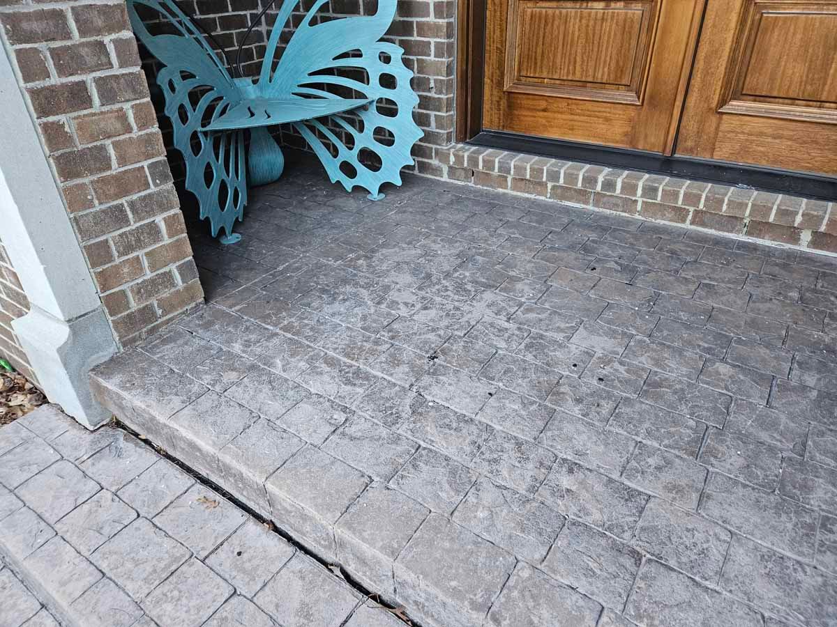 Stone front porch with brick trim, wooden door, and turquoise metal decor in the corner