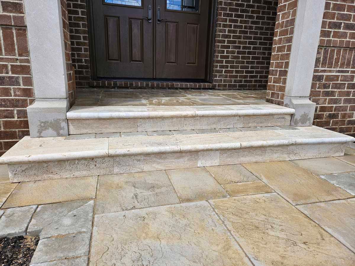 Stone steps leading to a dark wooden front door on a brick building