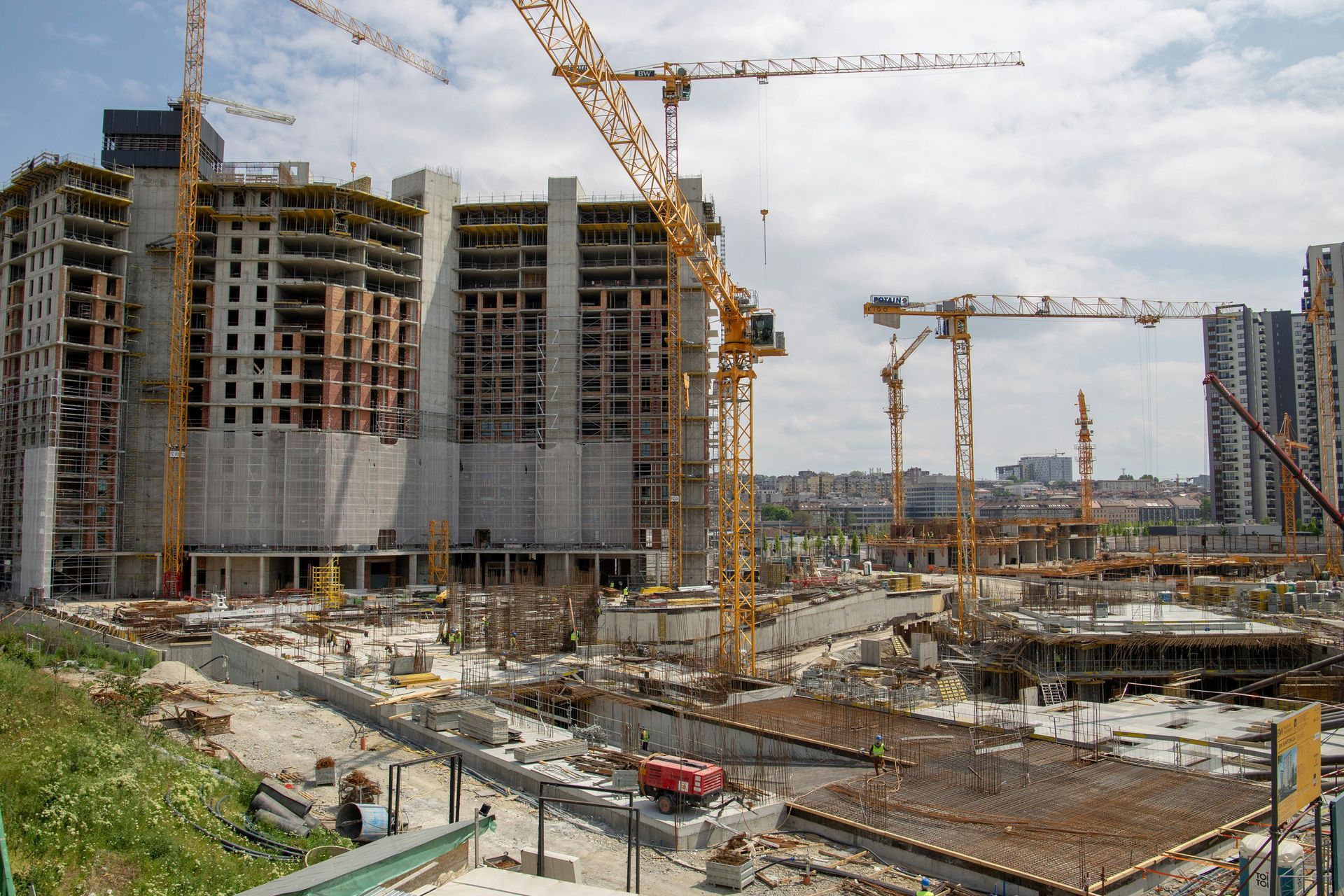 Large construction site with cranes and partially built high-rise buildings under an overcast sky
