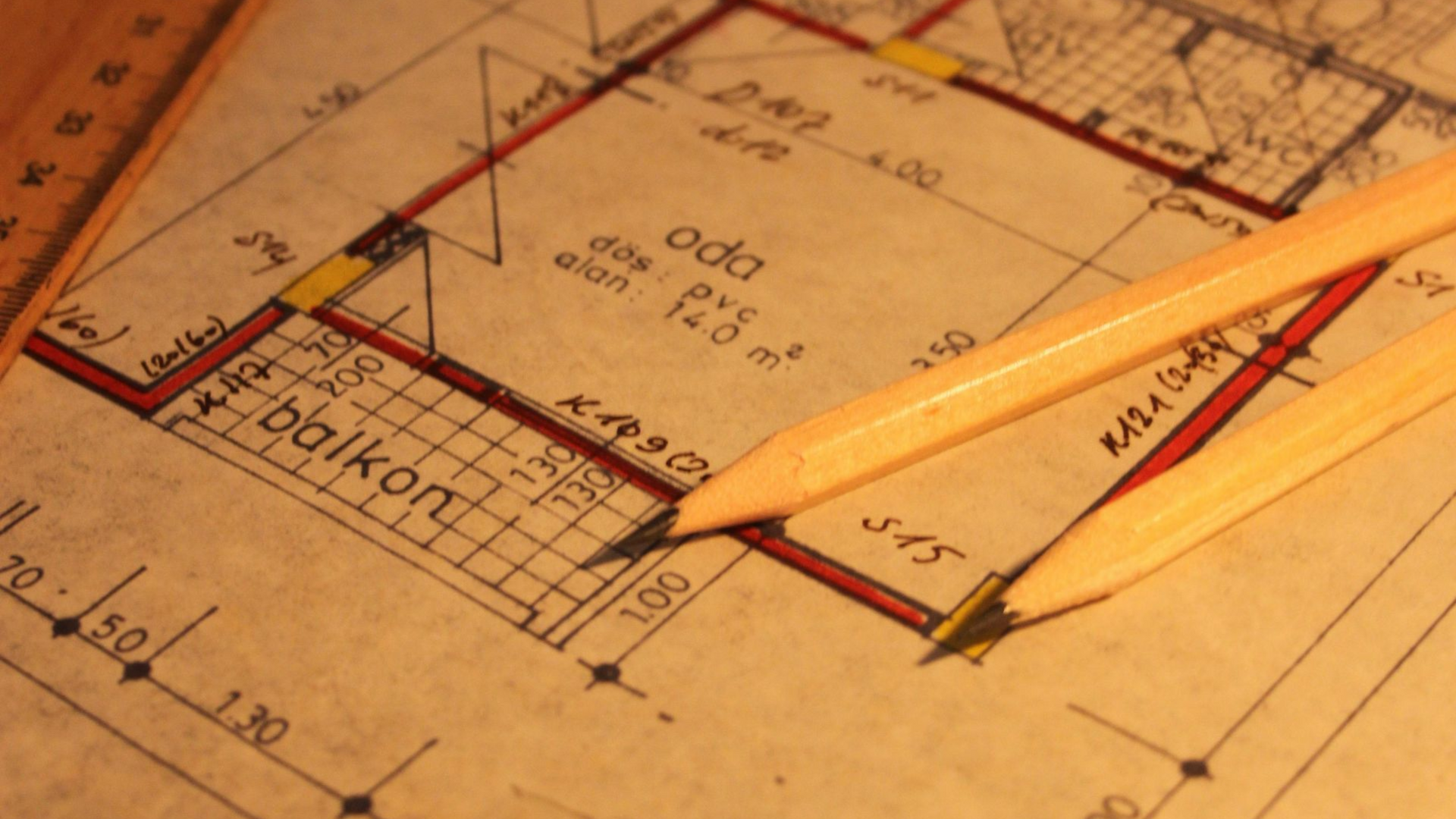 Architectural blueprint with two pencils on a warm-toned drafting table