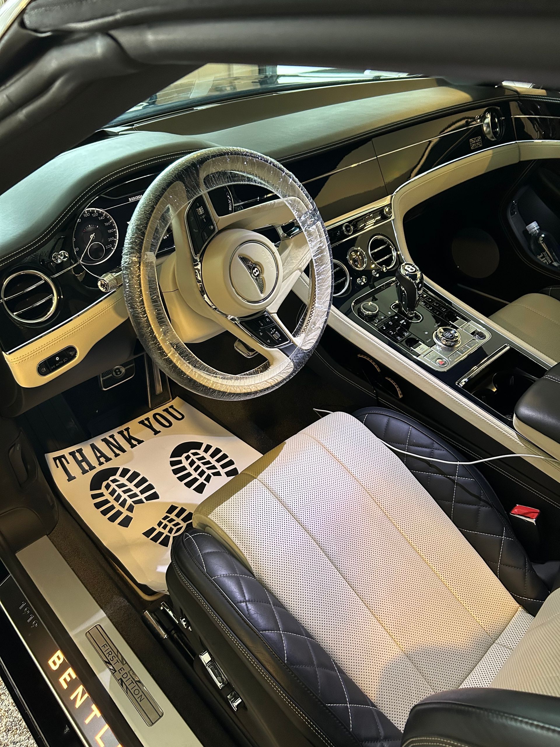 A person wearing a black glove wipes a car's shiny surface with a blue microfiber cloth, likely cleaning it.