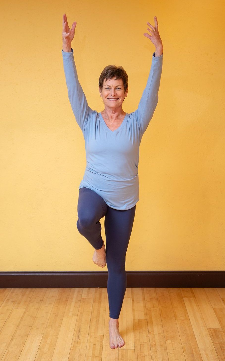 a woman in a black tank top and leopard print leggings is laughing