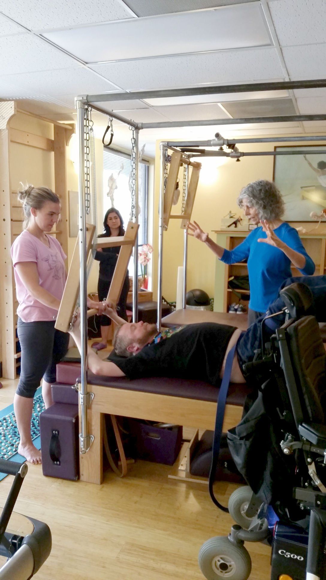 A group of people are doing exercises on a pilates machine in a studio