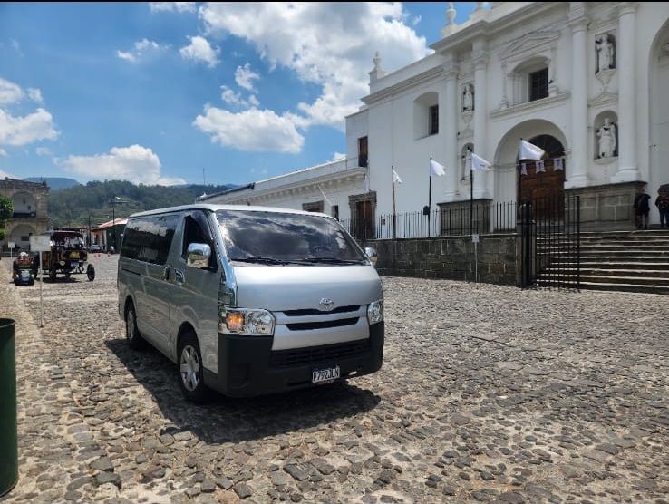 Un SUV negro estacionado en una calle mojada junto a un muro marrón, con la parte delantera orientada hacia la cámara.