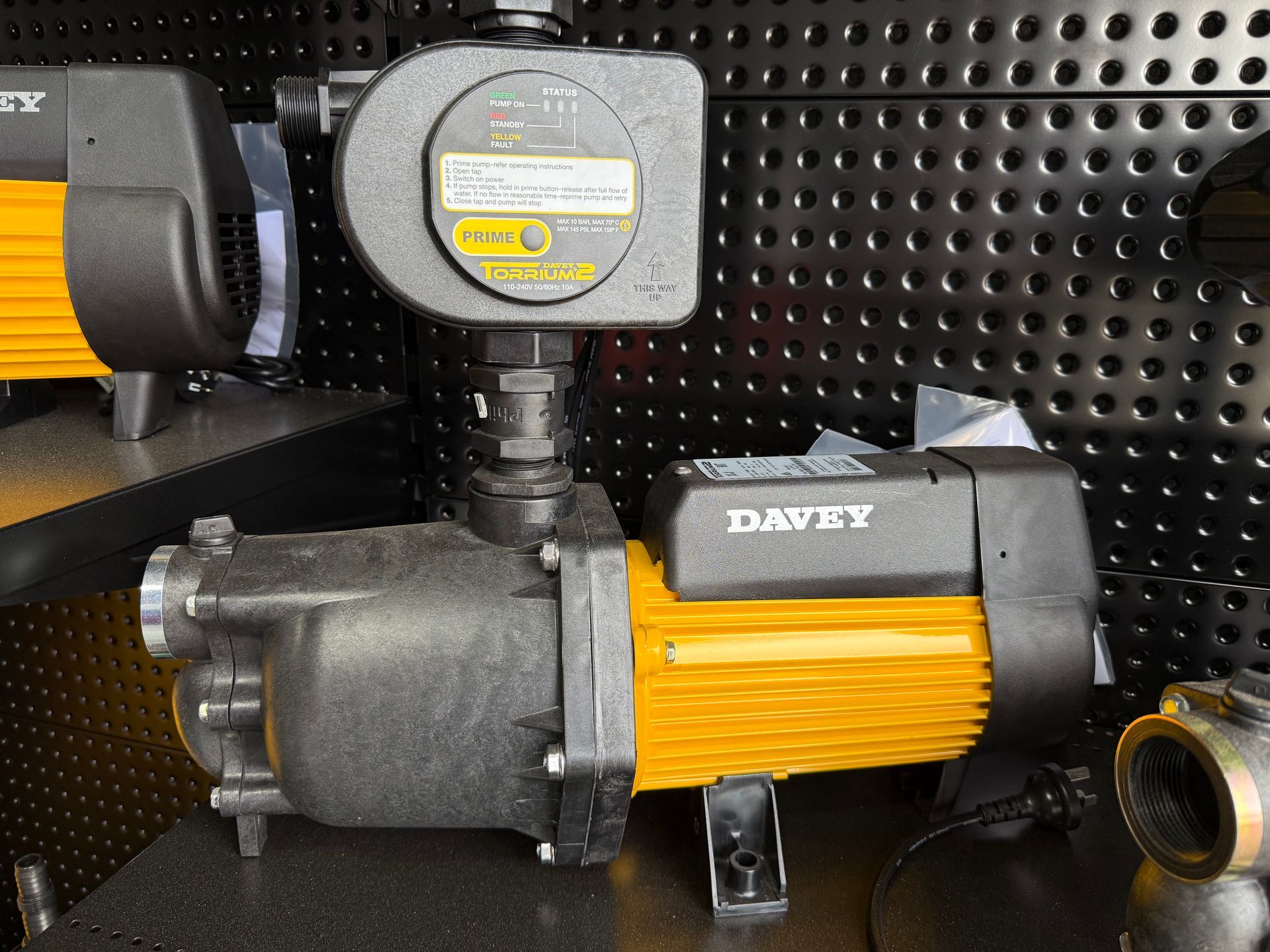 Black and yellow Davey water pump with pressure gauge on a pegboard display — Taree Water Works in Taree, NSW