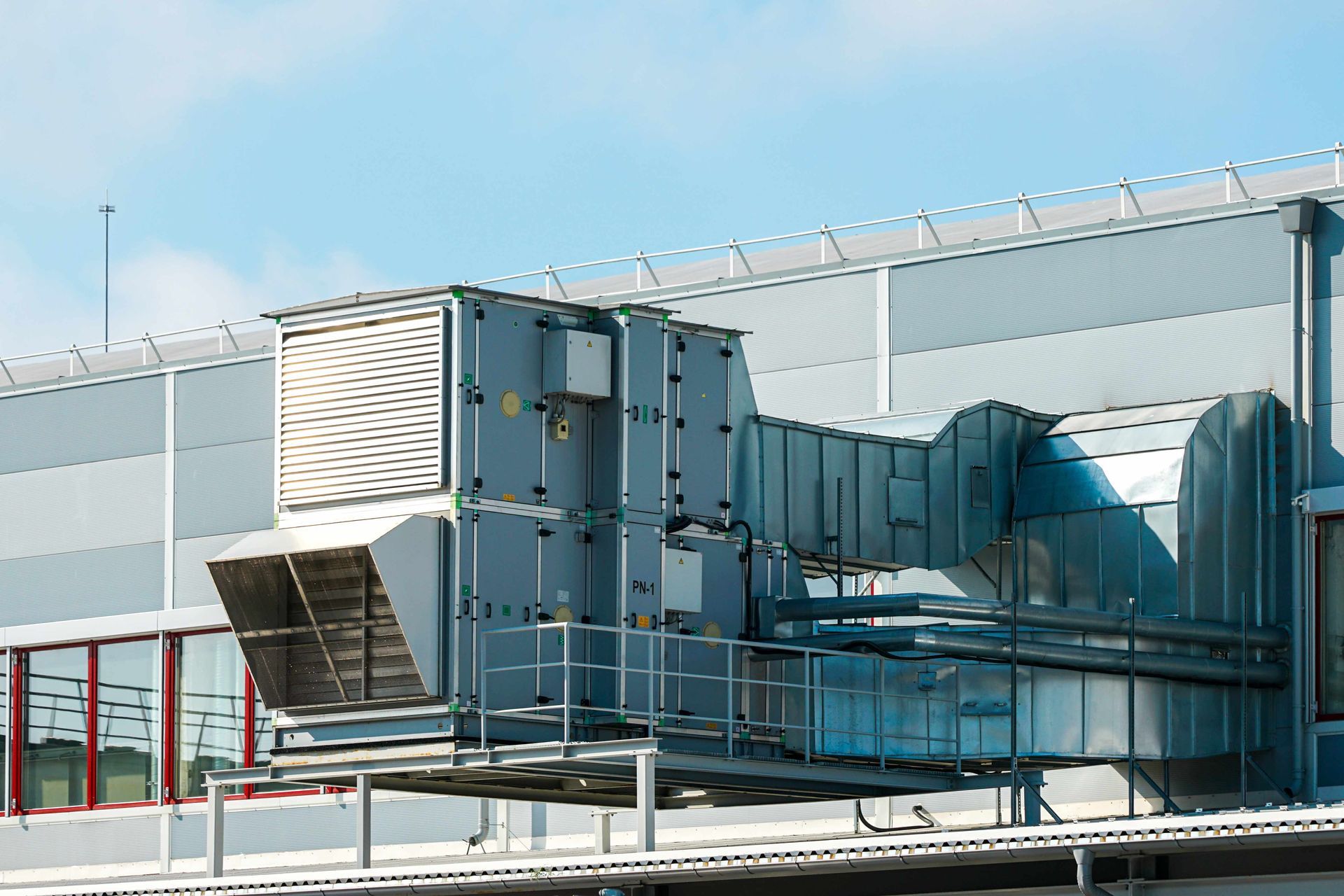 Industrial rooftop HVAC ductwork and ventilation units on a building exterior under a clear sky Industrial rooftop HVAC ductwork and ventilation units on a building exterior under a clear sky