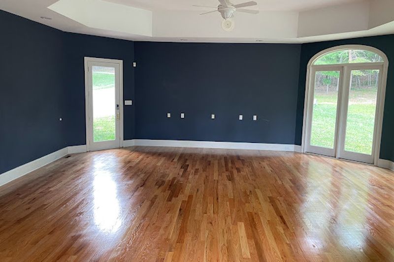 Empty room with dark blue walls, white trim, and hardwood floors. Two sets of French doors, white ceiling.