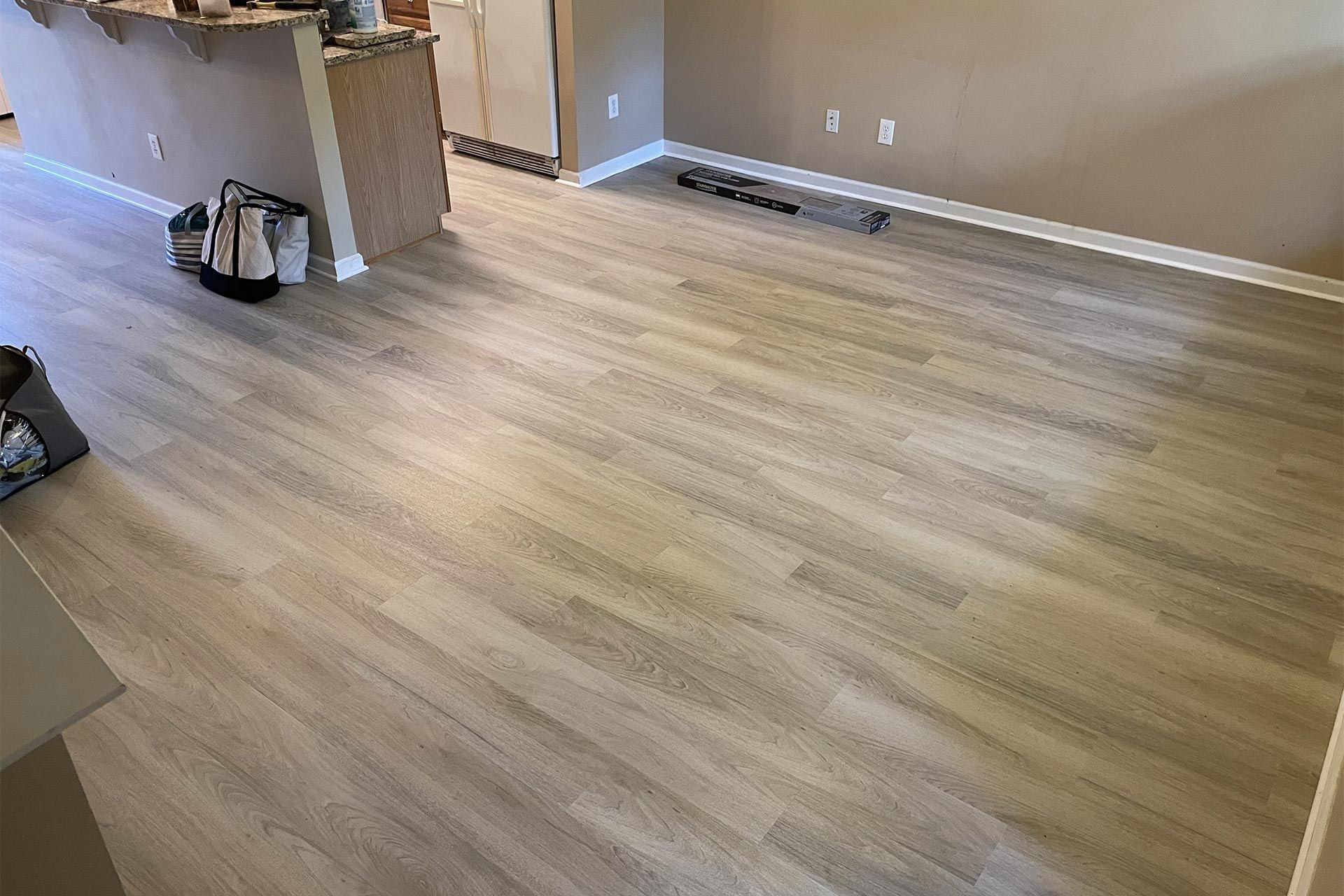 Light-colored wood-look flooring in a room with a partial wall, white trim, and beige walls.