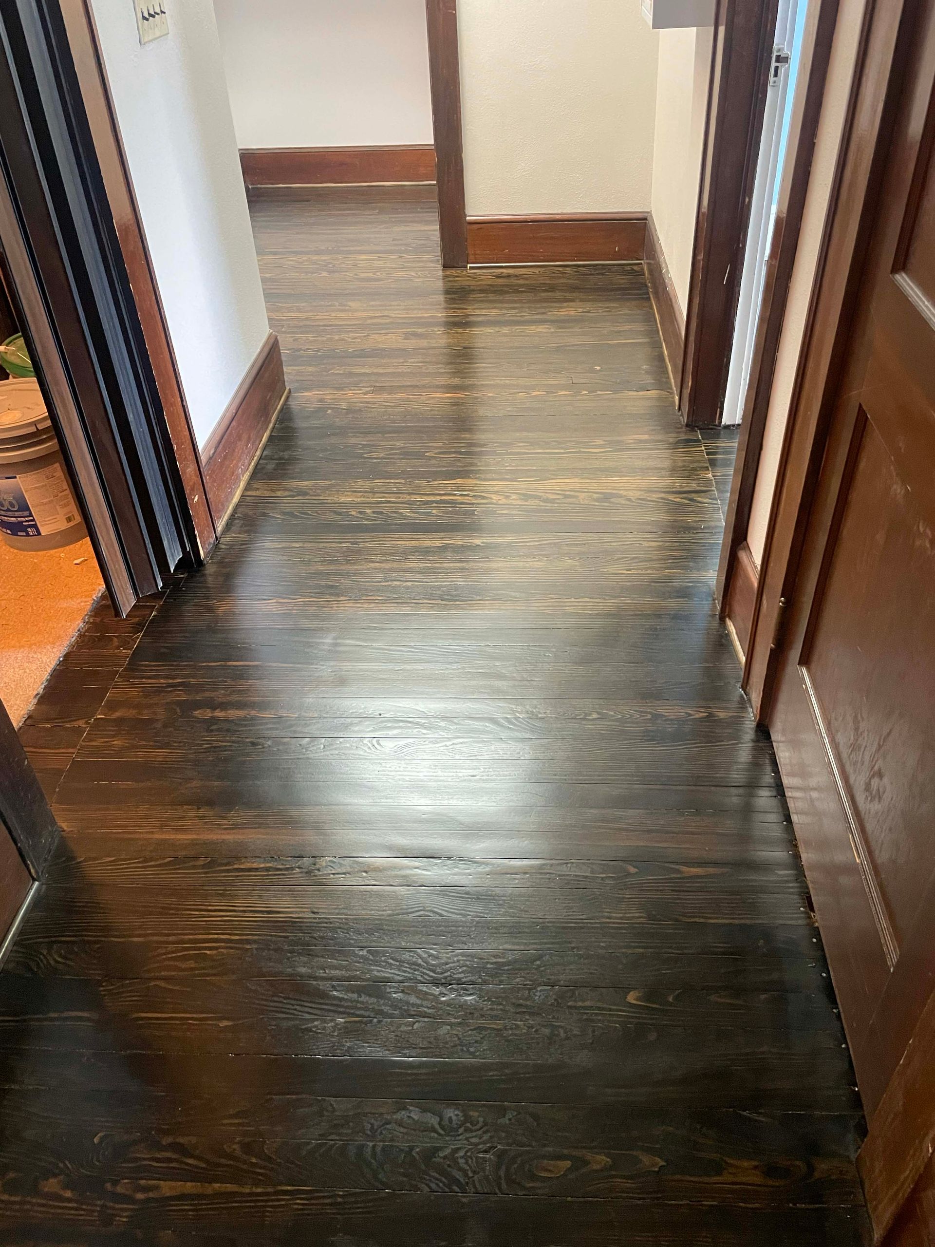 Dark wood hallway with distressed flooring and brown trim.