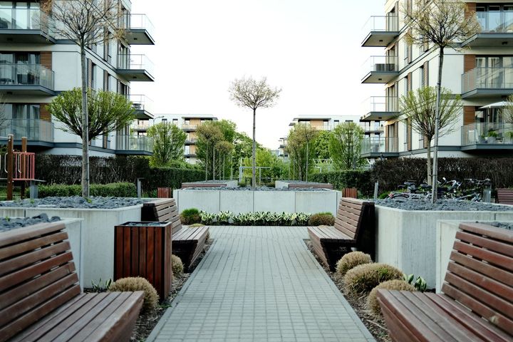 Modern apartment courtyard with benches, landscaped planters, and a paved walkway between buildings