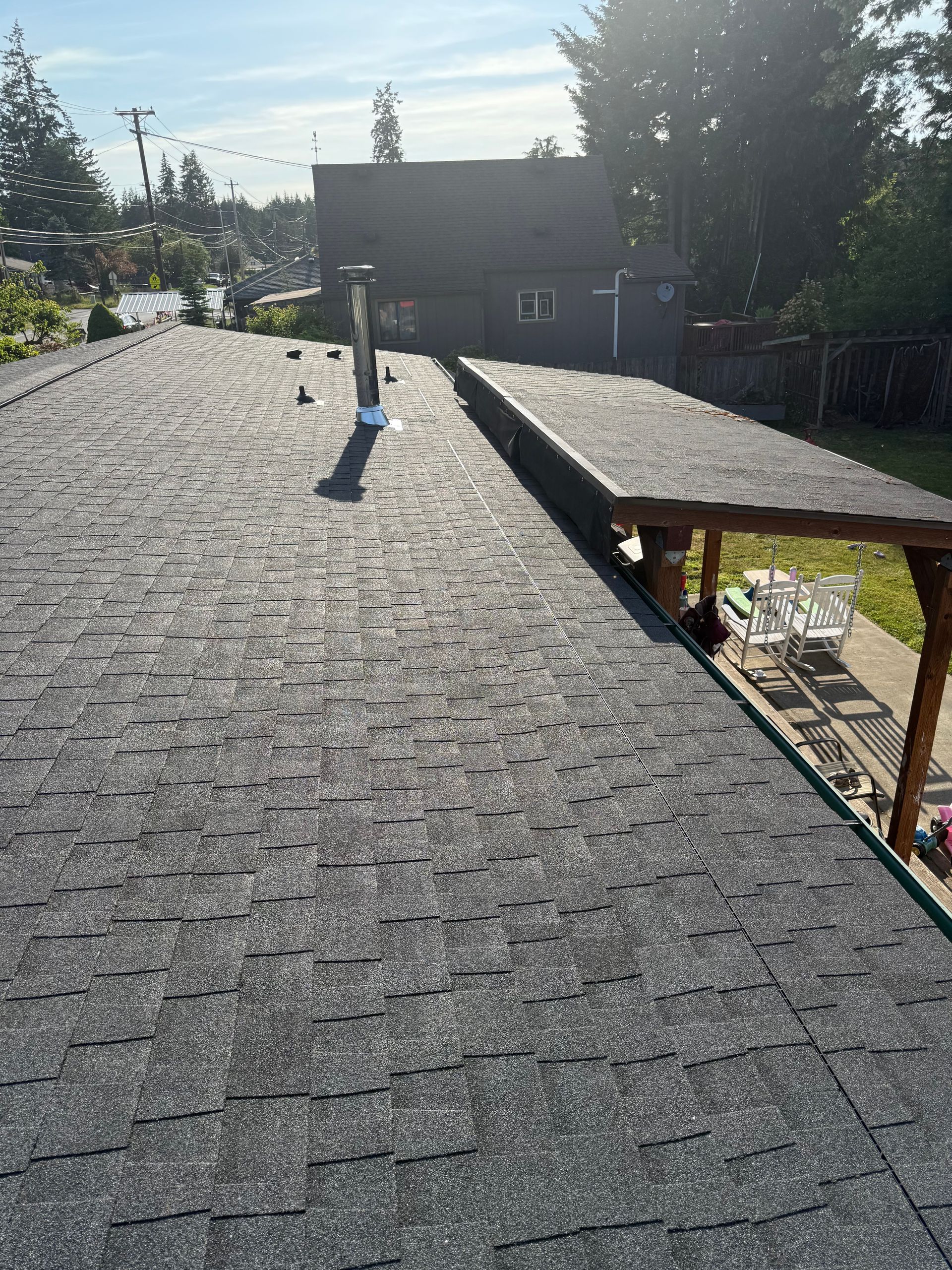 Gray shingled roof with a dark gray extension. Chimney and support beams visible. Sunny outdoor setting.