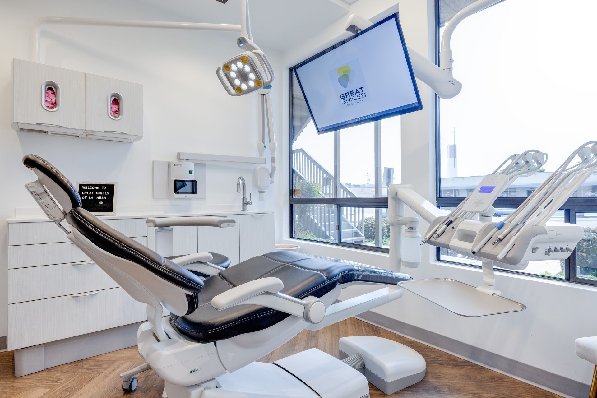 A dental office with a dental chair and a television on the wall.