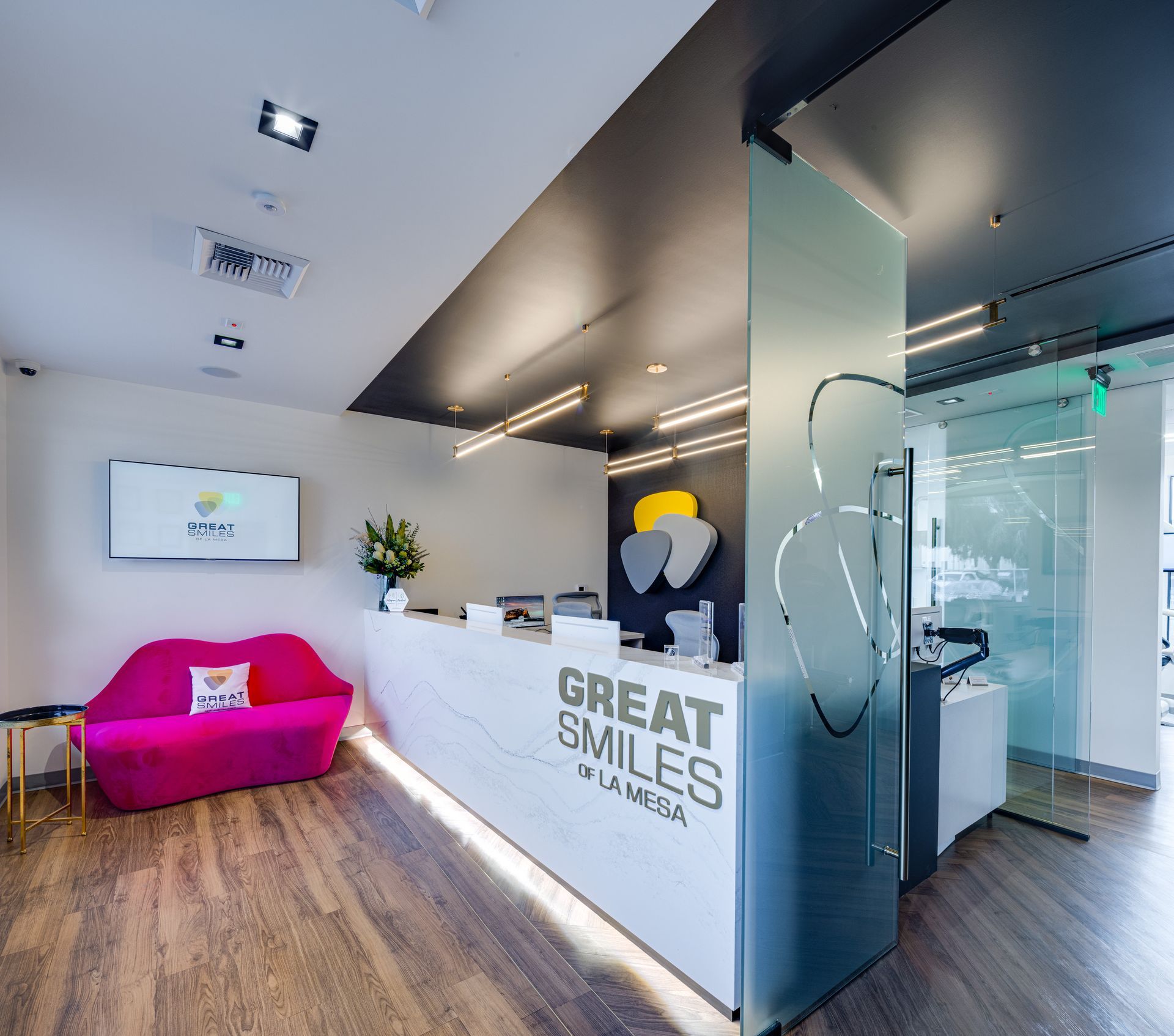 A dental office with a pink couch and a counter that says great smiles