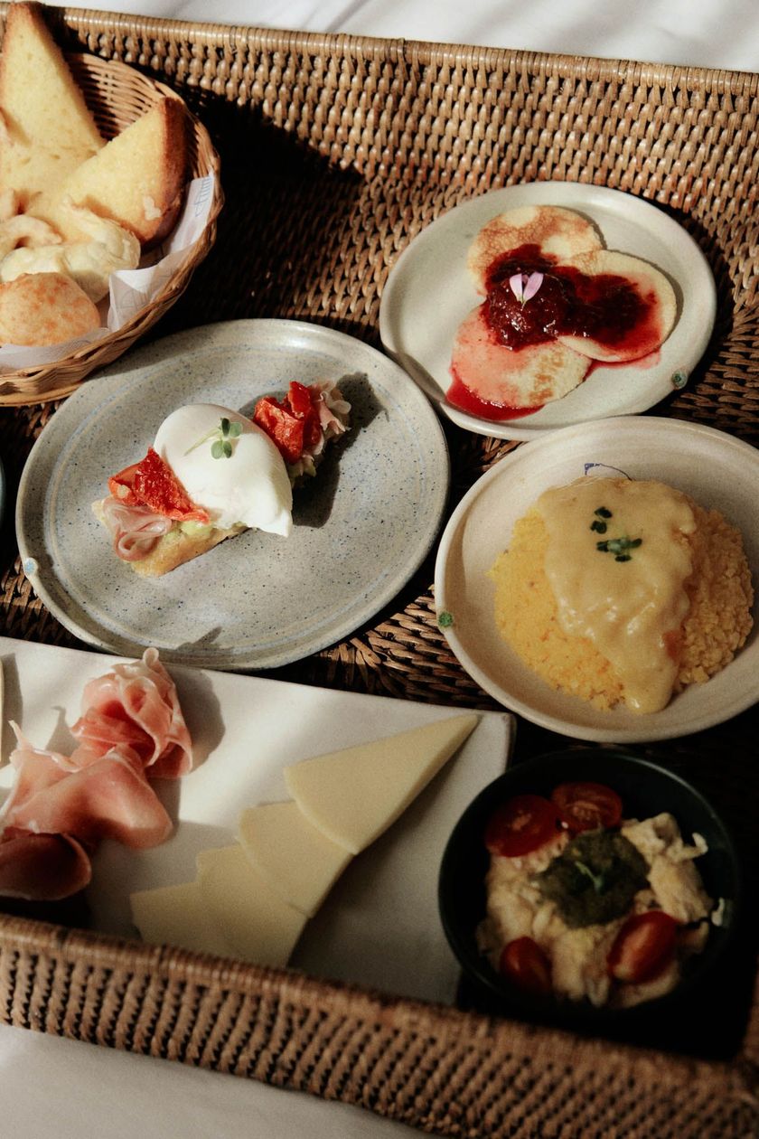 Aperitivos variados e pão servidos em pratinhos dentro de uma bandeja de vime.