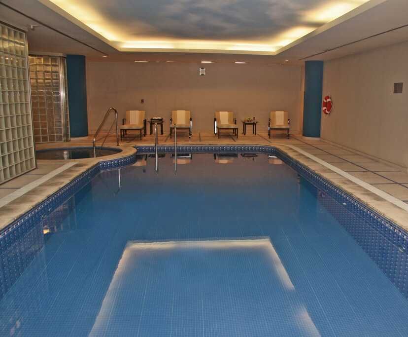 Una gran piscina cubierta con sillas alrededor.