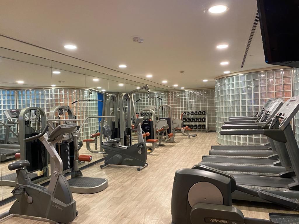 Un gran gimnasio con mucho equipamiento y muchos espejos.