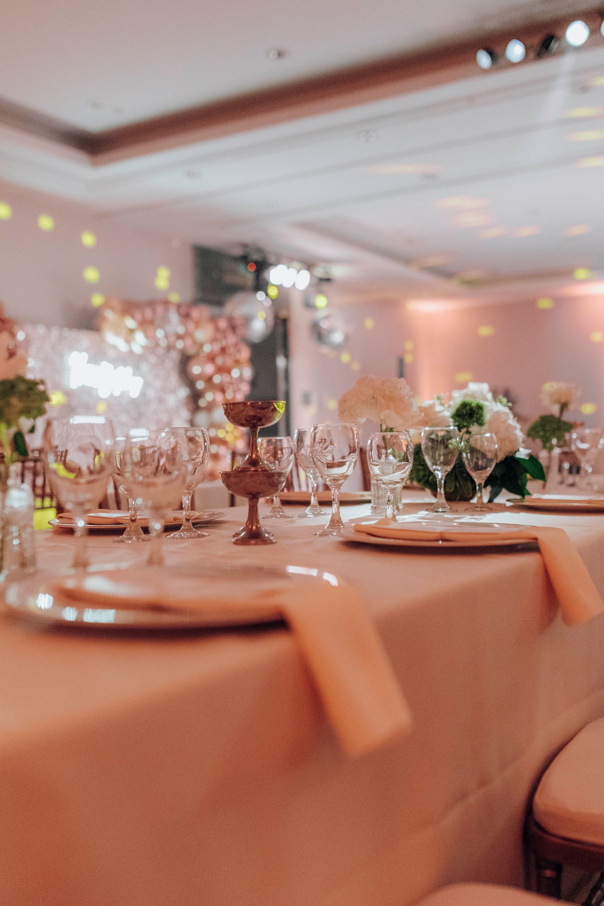 Una mesa con flores y linternas en una habitación con mesas y sillas.