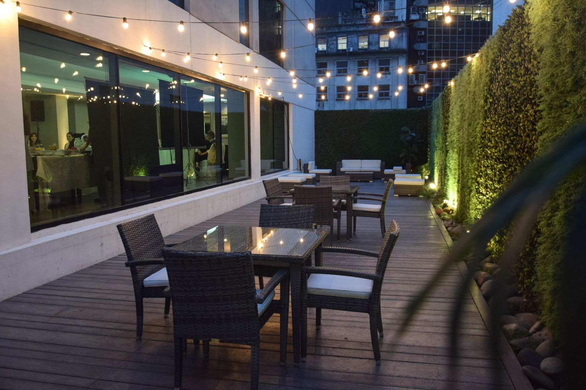 Una mesa y sillas en una terraza de madera con luces colgando del techo.