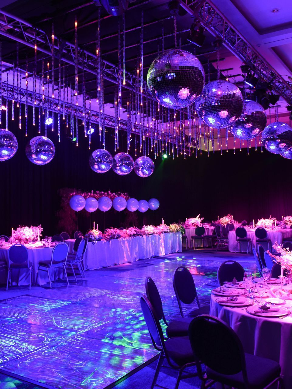 Una gran sala con mesas y sillas y bolas de discoteca colgando del techo.