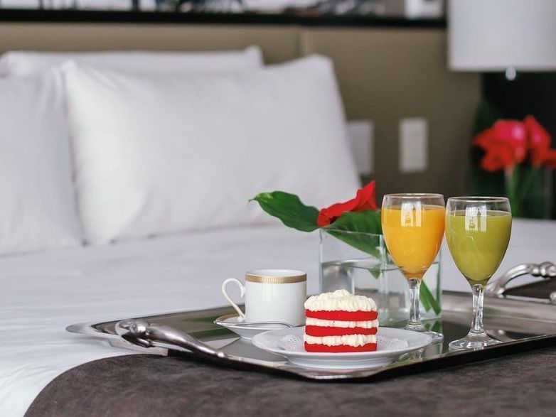 Una habitación de hotel con una bandeja de comida y bebidas en la cama.