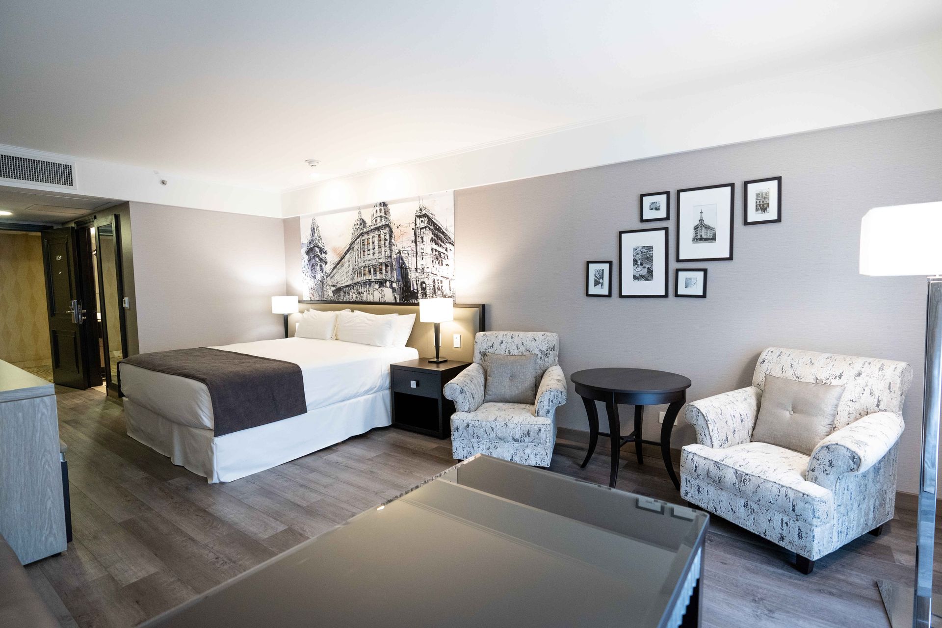 Una habitación de hotel con una cama tamaño king, dos sillas y una mesa.