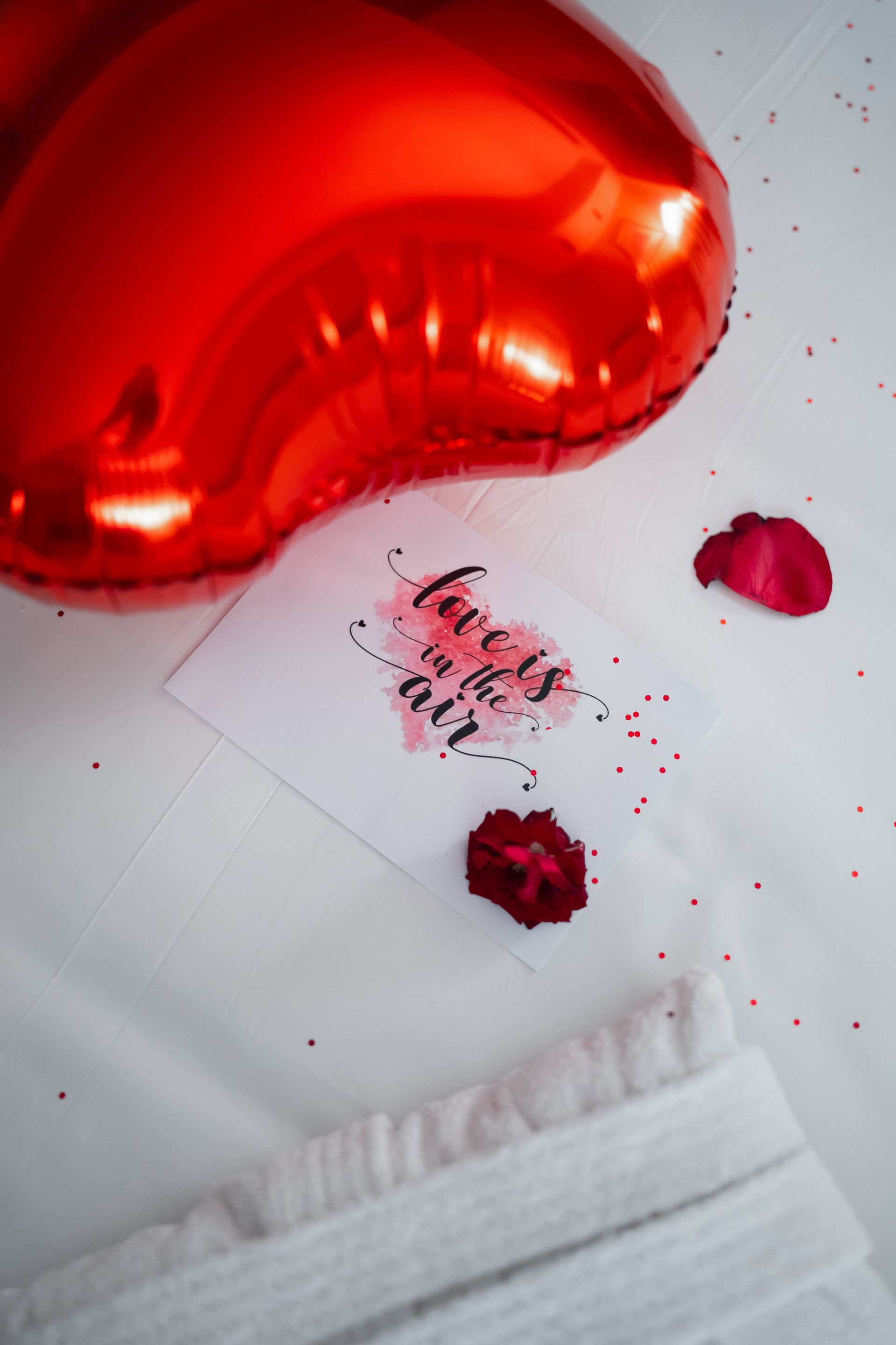 Un globo rojo en forma de corazón está junto a una tarjeta que dice que el amor está en el aire.